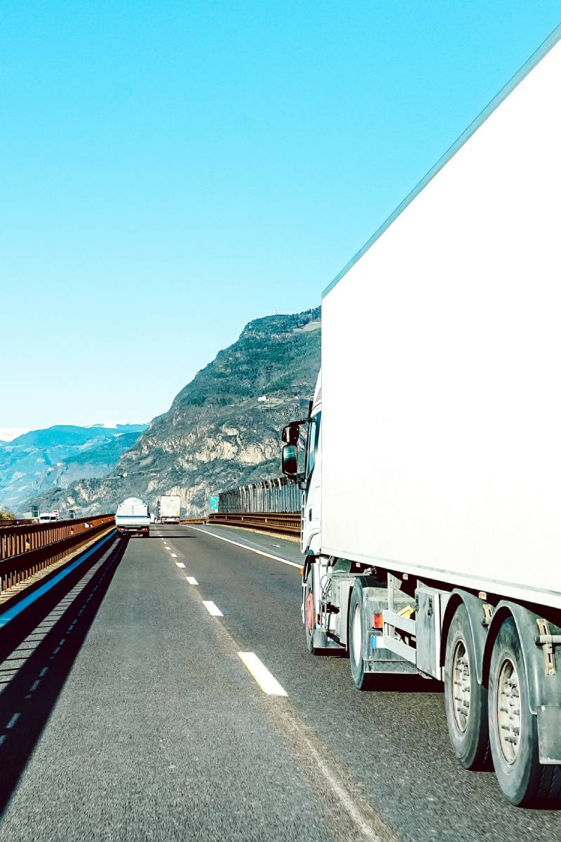 Semi truck speeding on empty highway line - Transport logistic concept with semitruck container driving on speedway - Focus on central part of background